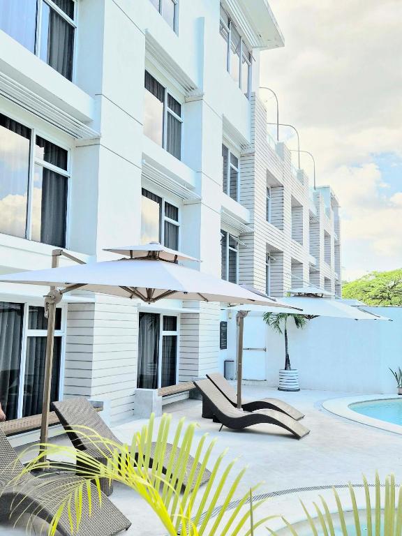 a patio with two umbrellas and chairs next to a building at LeBlanc Hotel in Antipolo