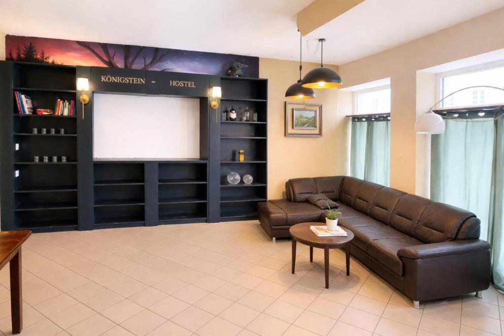 a living room with a brown leather couch and a screen at Königstein Hostel in Königstein an der Elbe