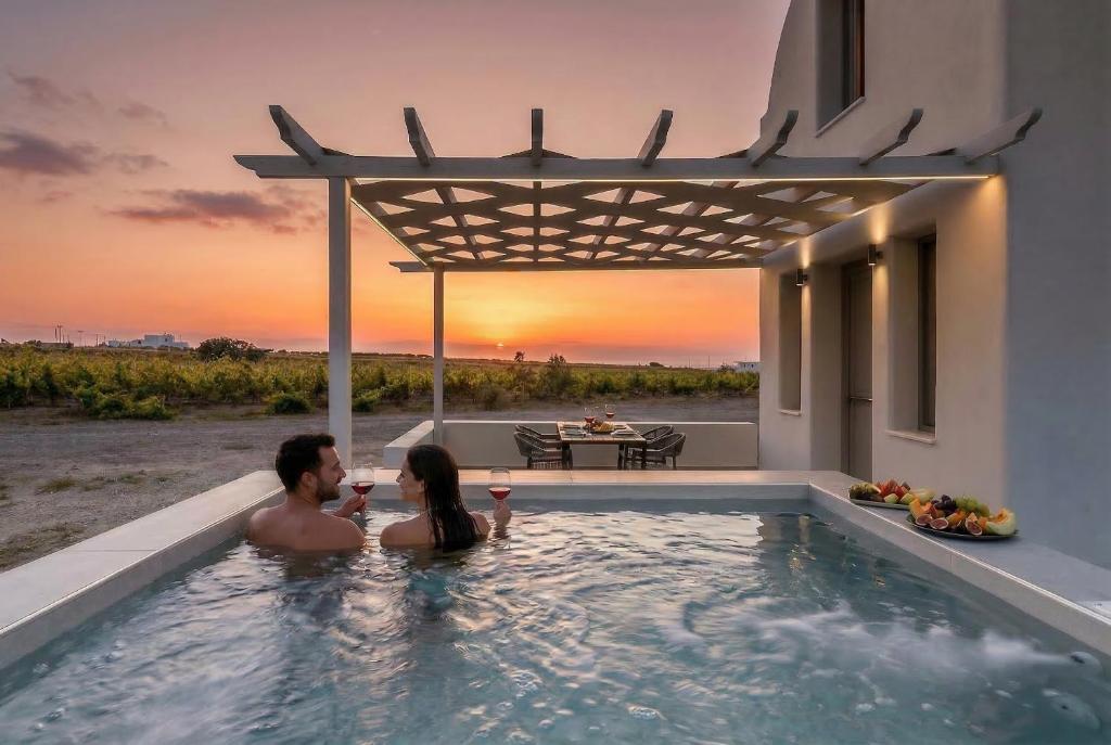 a man and a woman in a swimming pool with the sunset at MelivOia - Sunset Jacuzzi Villas in Foinikiá
