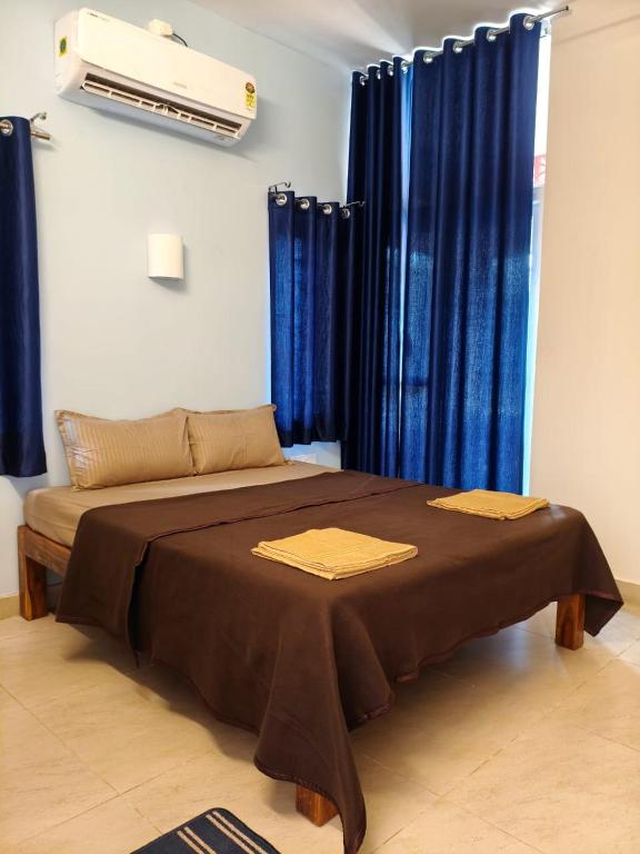a bedroom with a bed with blue curtains at La Maison D'Ellappa in Auroville