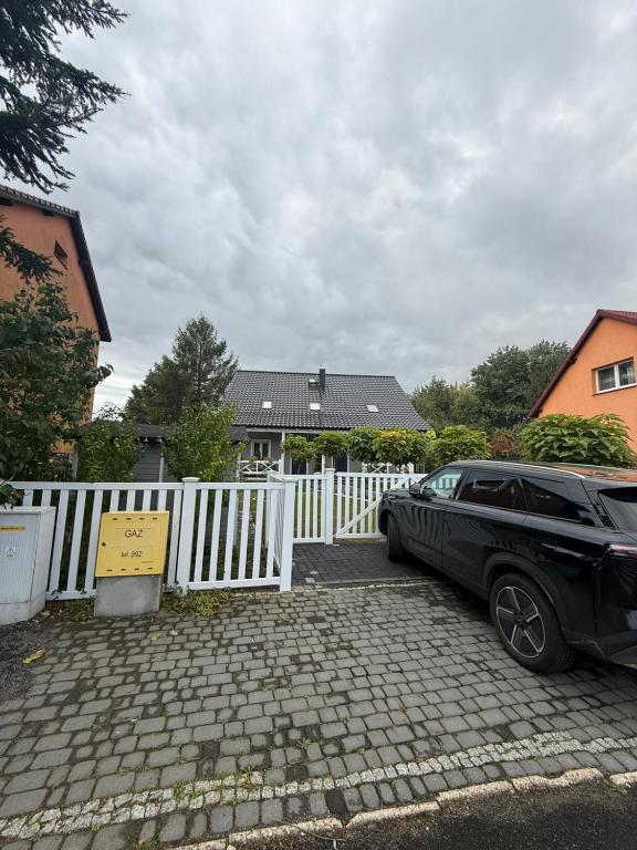 a black car parked in front of a white fence at Apartament Premium Pola in Bolesławiec