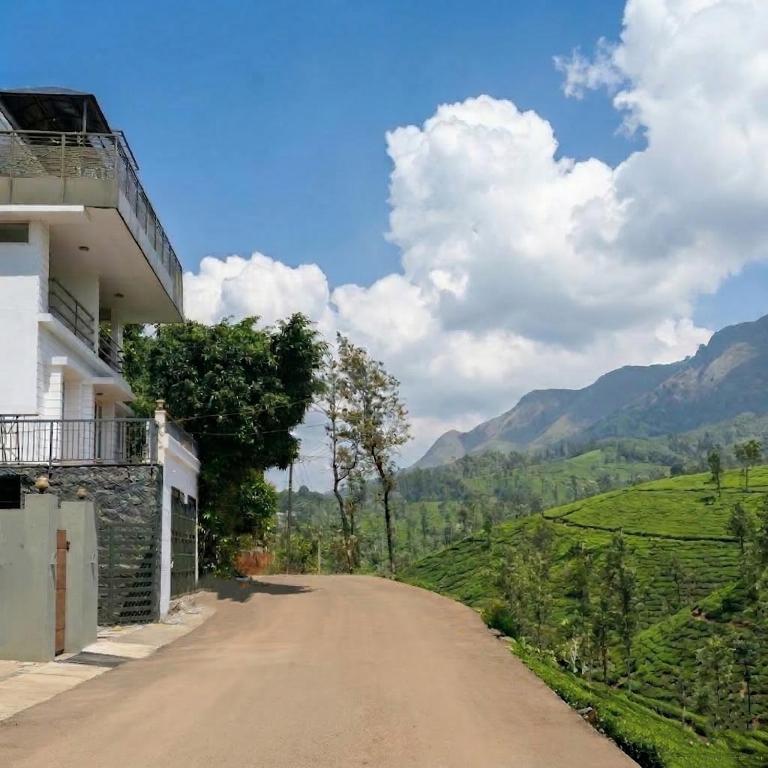 a dirt road next to a building with mountains in the background at Hill View Vythiri Holiday Home in Vythiri