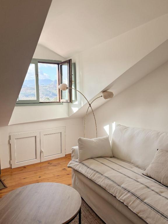 a white living room with a couch and a table at La ventanuca del Valle in Bielva