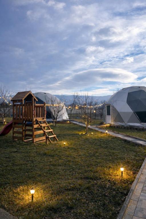 a tent and a playground in a field with lights at Sun Garden Glamping Domes in Călimăneşti