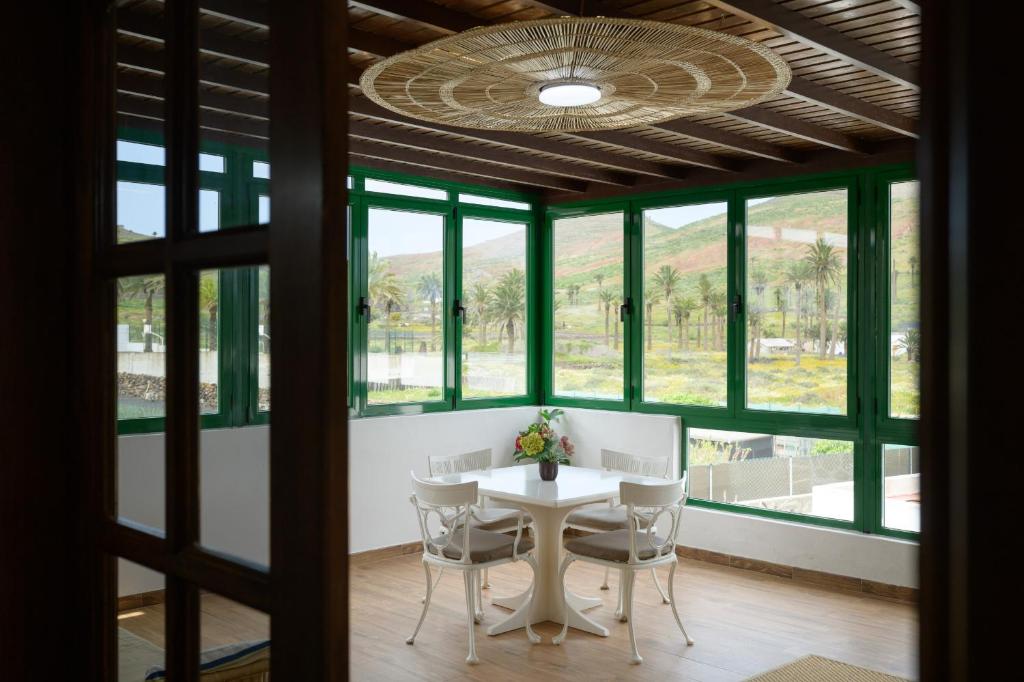 a dining room with a table and chairs and windows at Casa Crisana in Haría