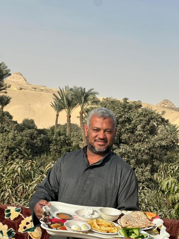 a man sitting at a table with a plate of food at Ancient Bakyard Guesthouse in Abū Şīr