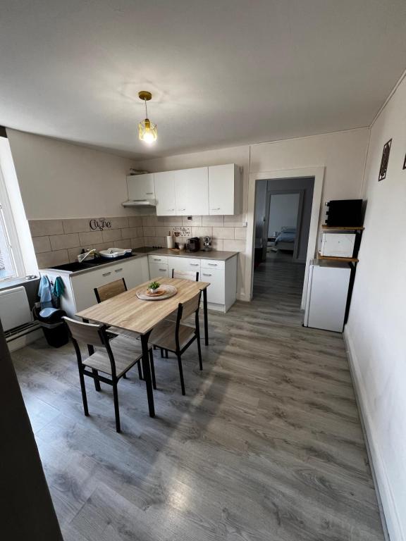 a kitchen with a table and chairs in a room at Appartement au 1 er étage côté jardin in Thaon-les-Vosges