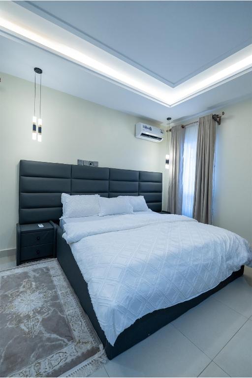 a bedroom with a large bed with a black headboard at Sanctum Suites in Abuja