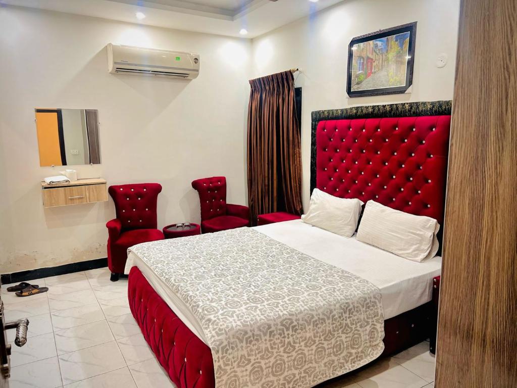 a bedroom with a red bed and two red chairs at Al Shahzan Hotel in Lahore