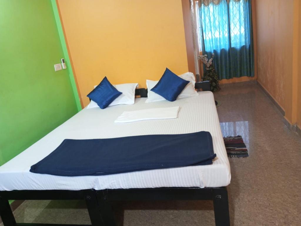 a bedroom with a bed with blue and white pillows at JBL Guest House , Arombal , Goa in Arambol