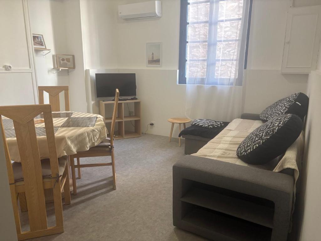 a living room with a couch and a table and a tv at Maison confort ombragé 2 chambres in Amélie-les-Bains-Palalda