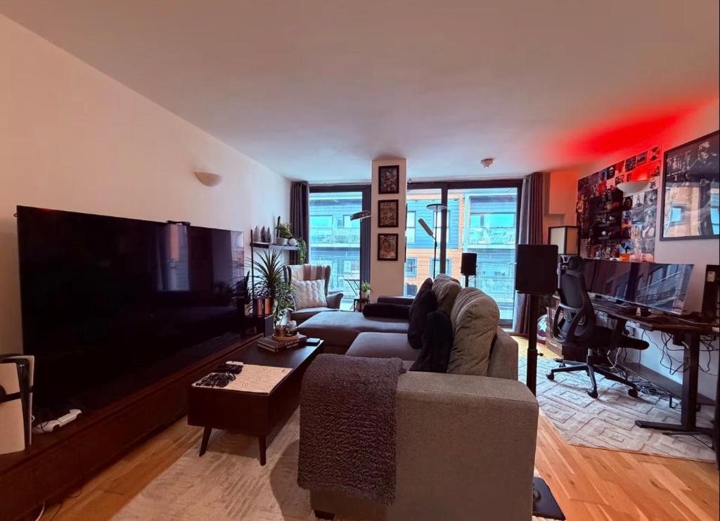 a living room with a couch and a large flat screen tv at Advent House Ancoats Hosted Apartment in Manchester