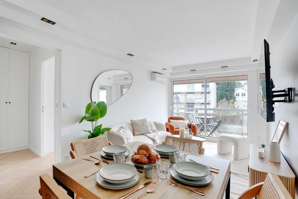a white living room with a table and a couch at Charming Apt with AC & balcony in Suresnes