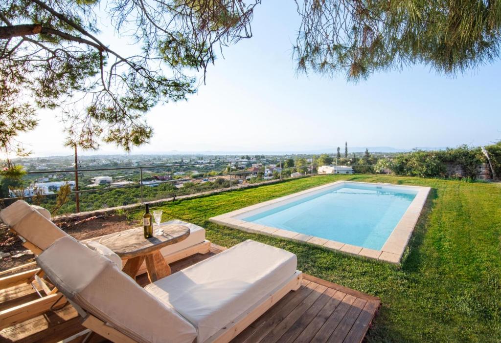 a swimming pool with chairs and a table and a pool at Majestique Villa Aegina in Egina