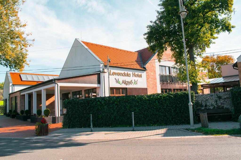 a building with an orange roof on a street at Levendula Hotel in Algyő