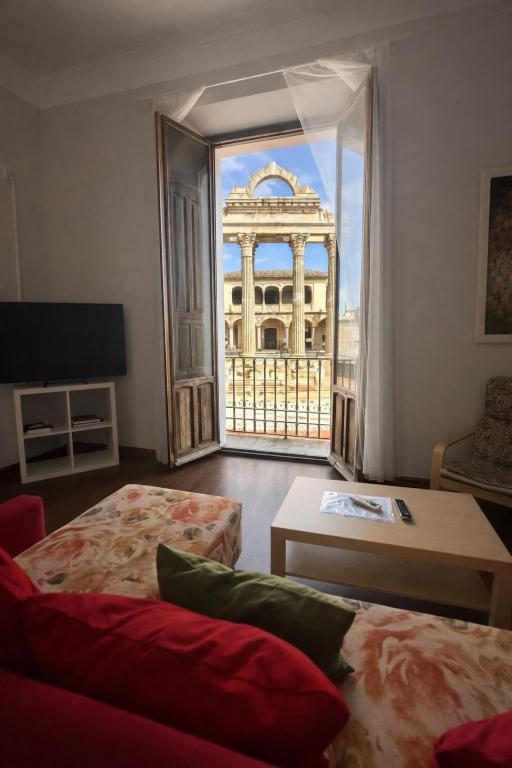 a living room with a view of a building through a window at Apartamentos Templo Diana -Vistas Históricas- in Mérida
