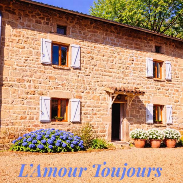 a brick building with flowers in front of it at L'Amour Toujours in Saint-Julien-le-Petit