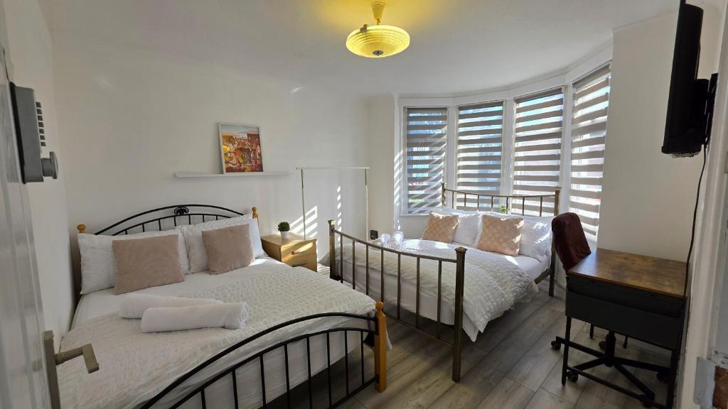 a bedroom with two beds and a desk and windows at Nice Living Serviced Accommodations 15 in Allesley