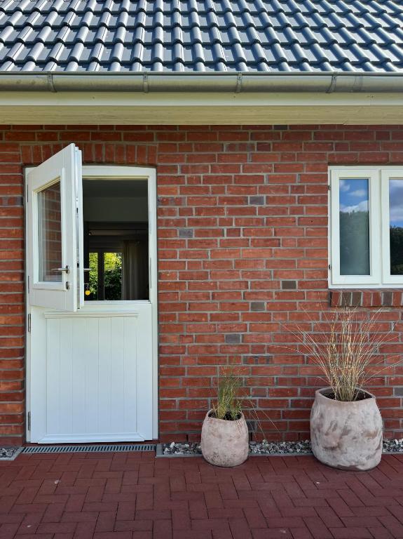a brick house with a white door and two potted plants at Nije Haven Bed & Breakfast in Wrixum
