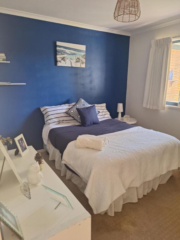 a bedroom with a bed with a blue wall at Helens Hideaway in Coronet Bay