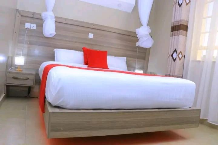 a bedroom with a large white bed with a red pillow at Ohm Village Inn in Kitui