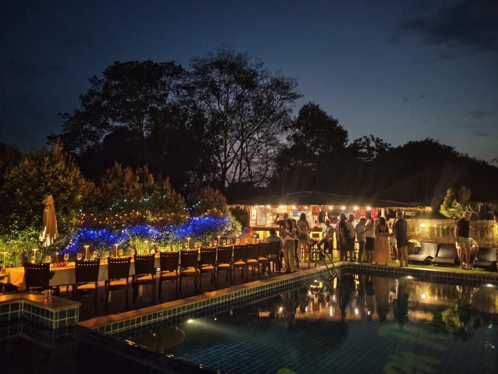 a group of people standing around a pool at night at IYARA b in Ban Map Khangkhao