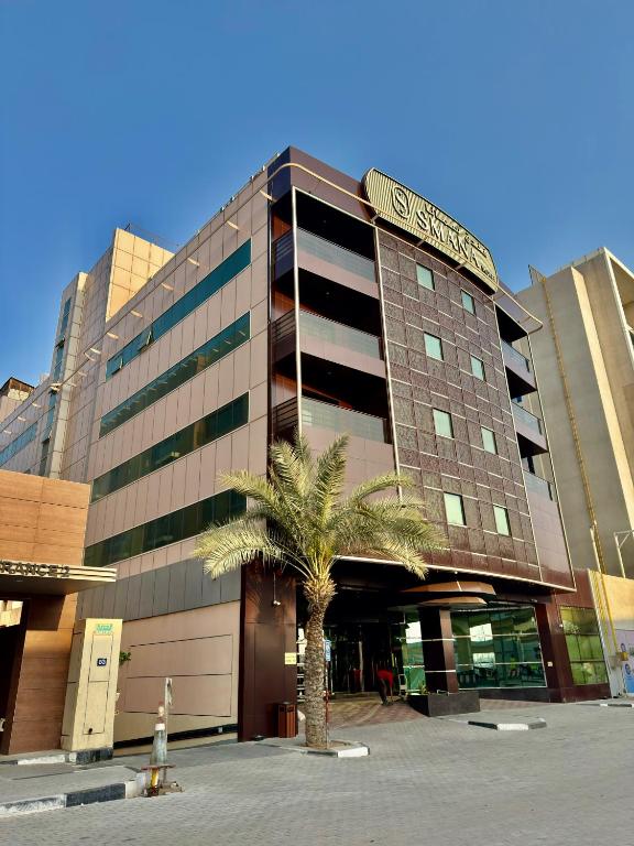 a building with a palm tree in front of it at Smana Hotel Al Raffa in Dubai