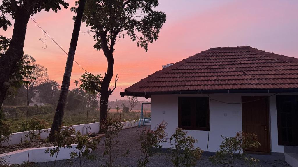 a house with a sunset in the background at Pebbles in Thirunelli