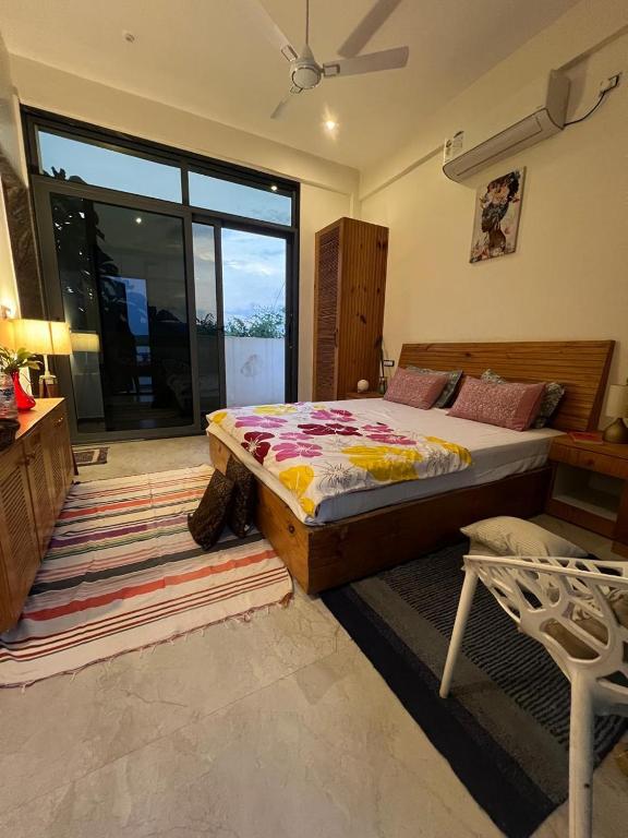 a bedroom with a bed and a large window at The Peace Corgaon in Corgao