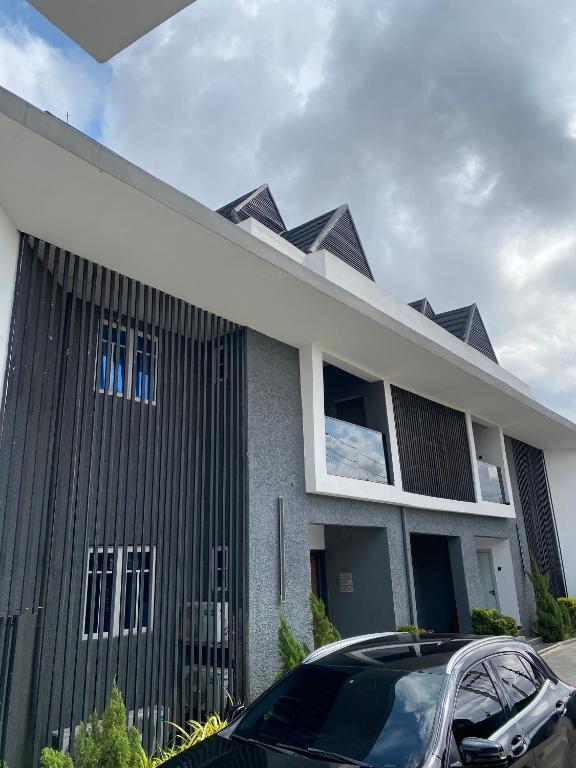 a black and white building with a car parked in front at Greyfield Apartment 1 in Benin City
