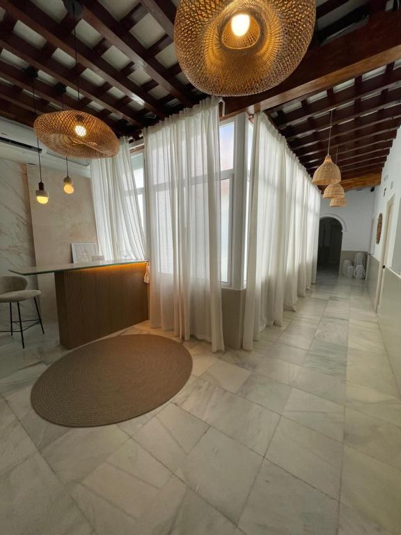 a large hallway with white curtains and a table at BOHEMIA SANLUCAR in Sanlúcar de Barrameda