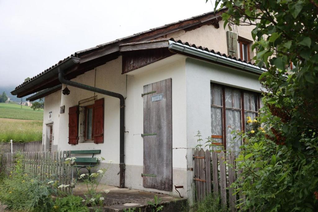a small white house with a door and a fence at Ferme en pleine nature in Boudevilliers
