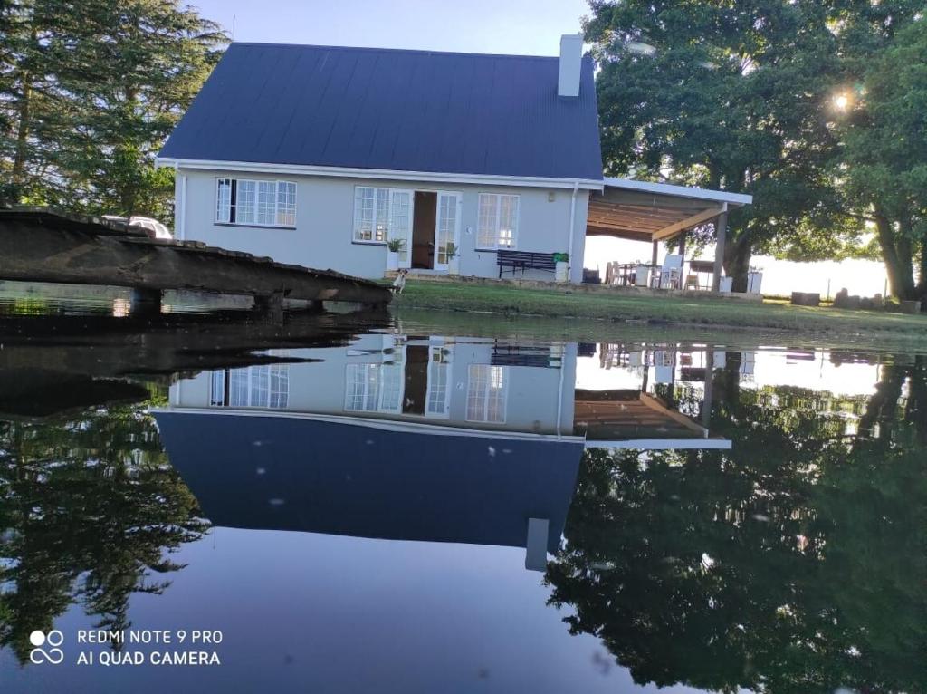 a house with a boat in the water at Lake Zonk Cottage in Mooiriver
