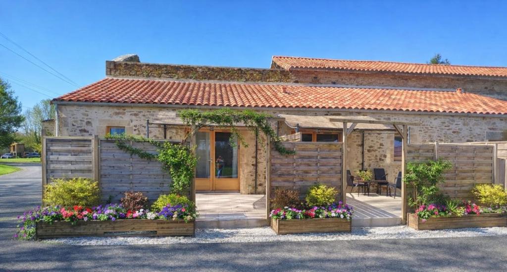 a stone house with flowers in front of it at Maisonnette de charme A 5 min du Parc PUYDUFOU in Les Épesses
