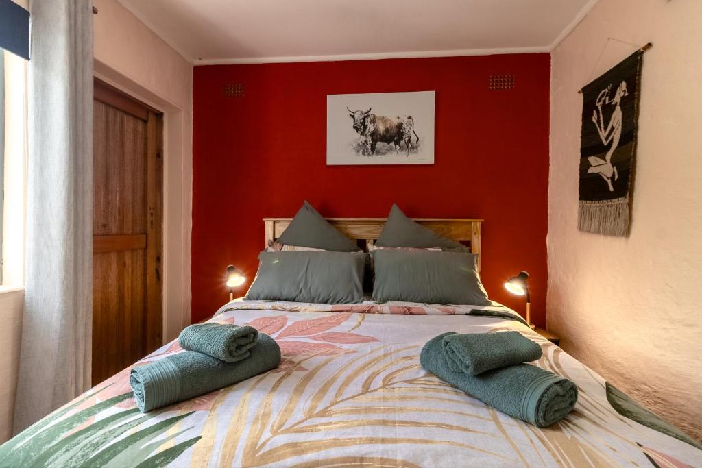 a bedroom with a large bed with a red wall at Birdsong Cottage in Howick