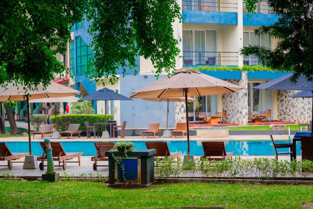 a pool with tables and chairs and umbrellas at Miridiya Lake Resort in Anuradhapura