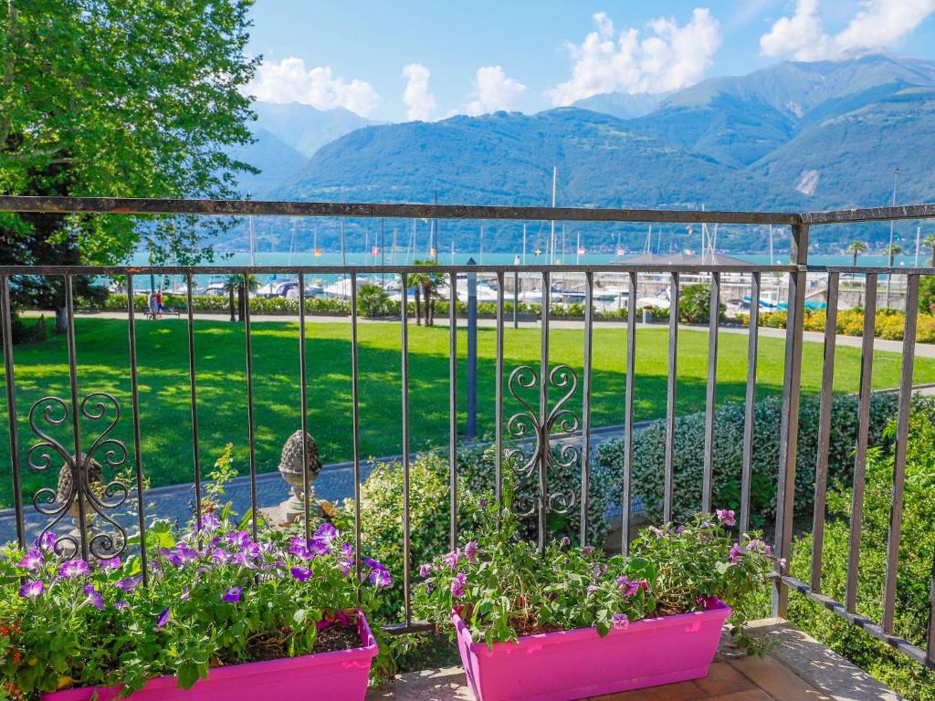 a garden with flowers and a fence with mountains in the background at Villa Lago Foreground Lakefront Beach Bike&Boat& Scooter Lake Como in Colico
