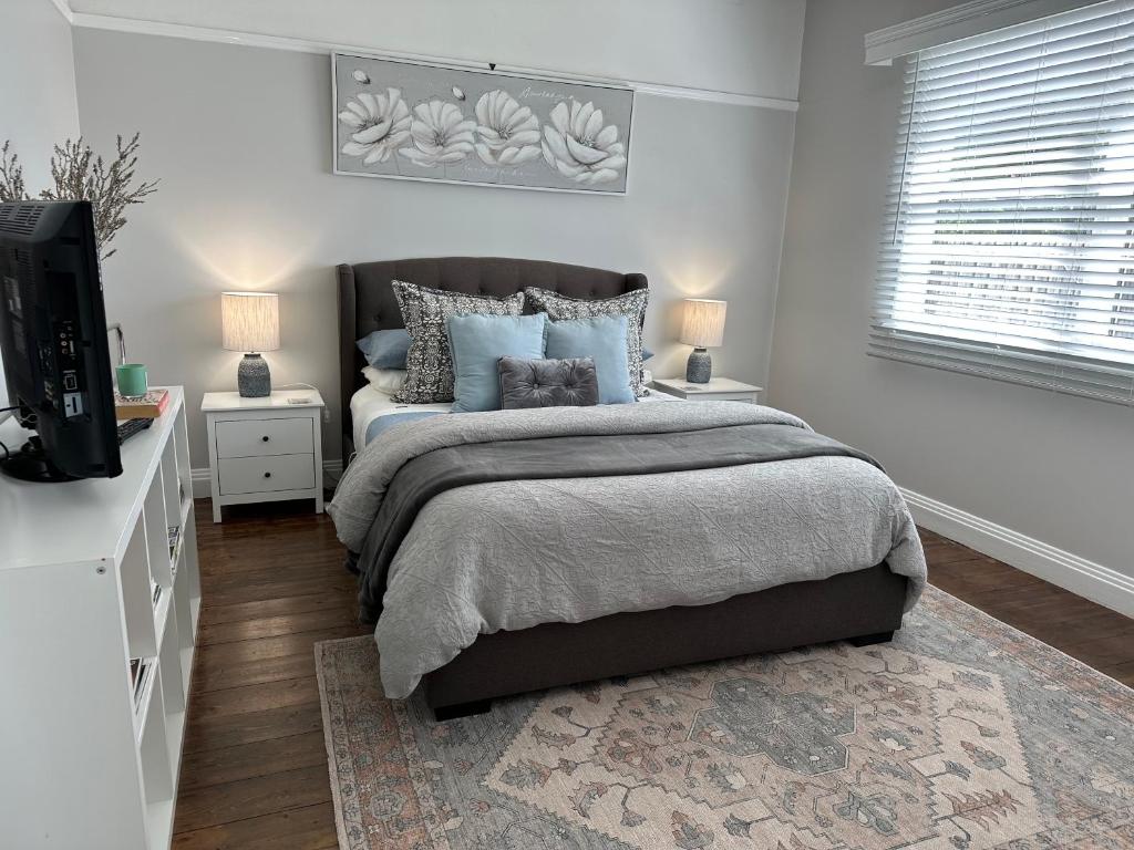 a bedroom with a bed with blue pillows and a television at Daisy Cottage on Duke 1BR in Yarram