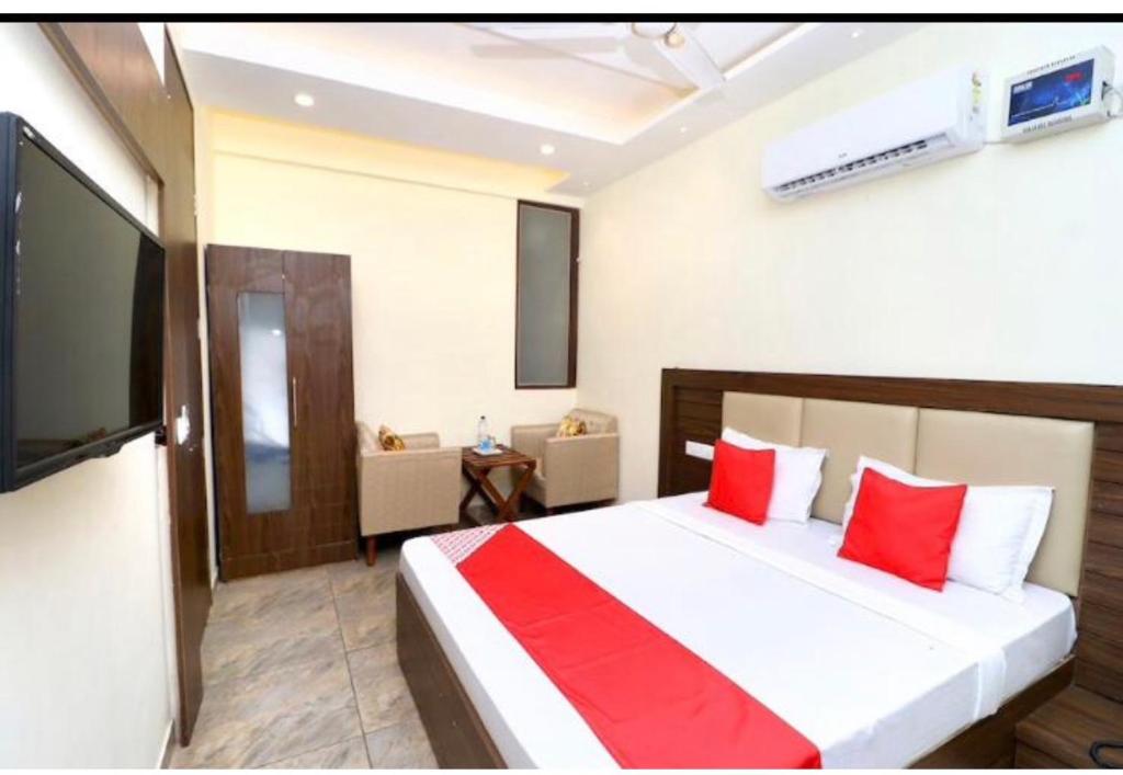 a bedroom with a bed with red pillows and a television at Jeevak hotel in Mohali