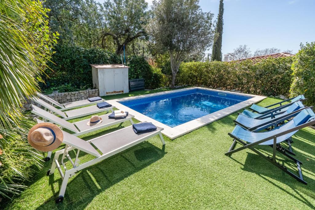a swimming pool with two lounge chairs and a table at Villa Les Moreres de Sitges in Sitges