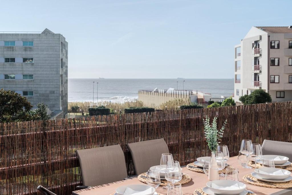 a table with plates and glasses on a balcony with the ocean at Spacious Seafront Residence - Family Friendly in Vila Nova de Gaia