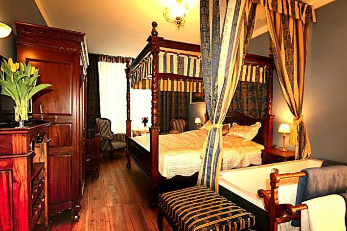 a bedroom with a canopy bed and a chair at Hotel Denkmal 13 Wismar in Wismar