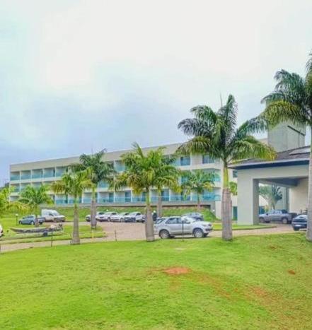 a large building with palm trees in front of it at Hotel Mirante São Brás in São Brás do Suaçuí