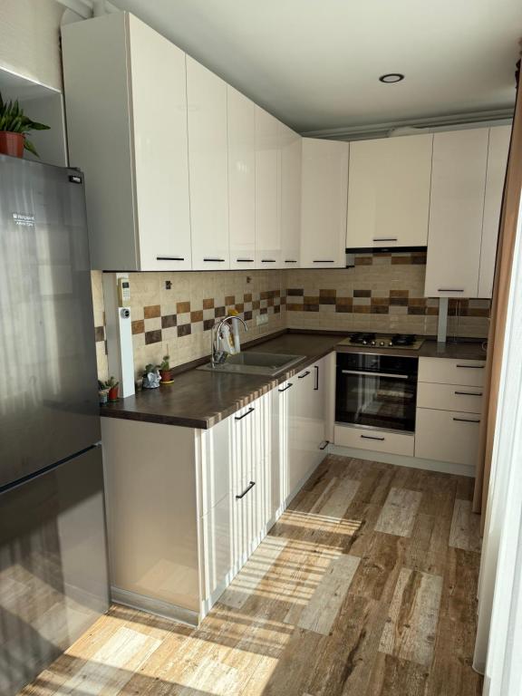 a kitchen with white cabinets and a wooden floor at Apartament Buiucani in Durleşti