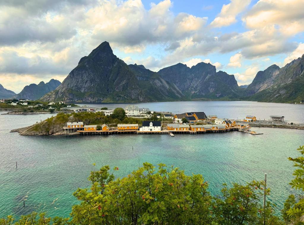 a small island in a body of water with mountains at Sakrisøy Rorbuer in Reine