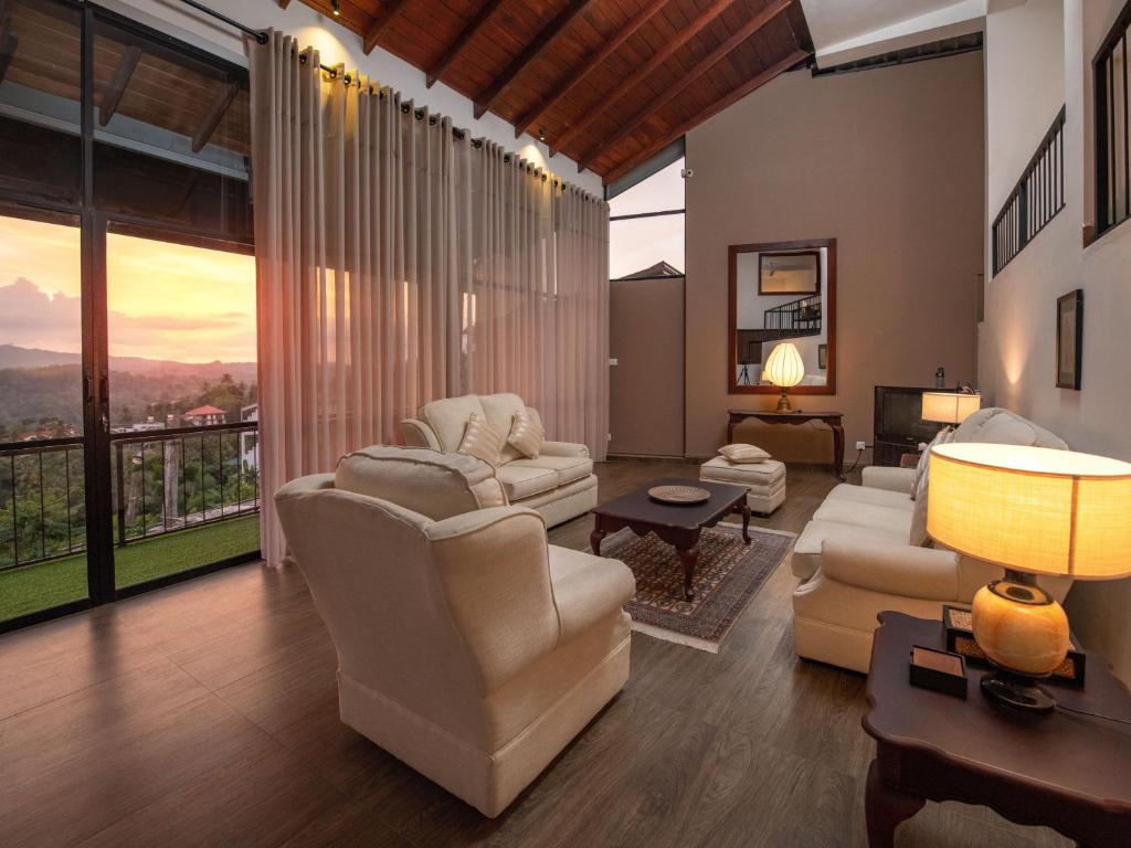 a living room with white furniture and large windows at Swarga Villa in Kandy