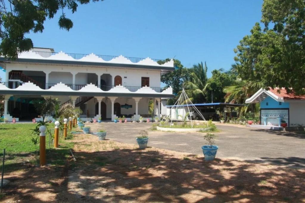 a building with potted plants in front of it at Rose Lagoon Hotel in Vakarai