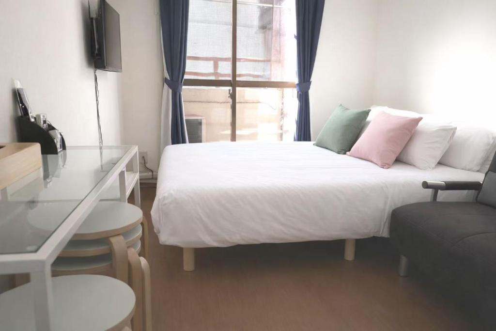 a bedroom with a bed and a desk and a window at House L in Shinjuku in Tokyo