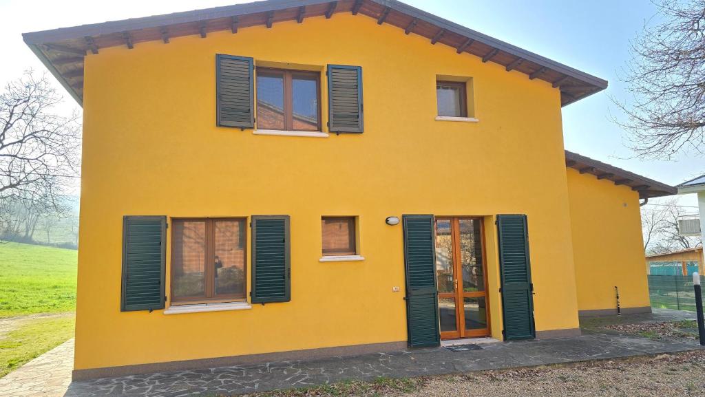 a yellow house with green shutters on it at La Nocina in Raggio