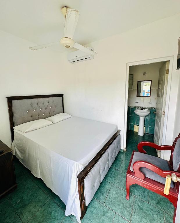 a bedroom with a white bed and a red chair at Hotel center in Las Terrenas